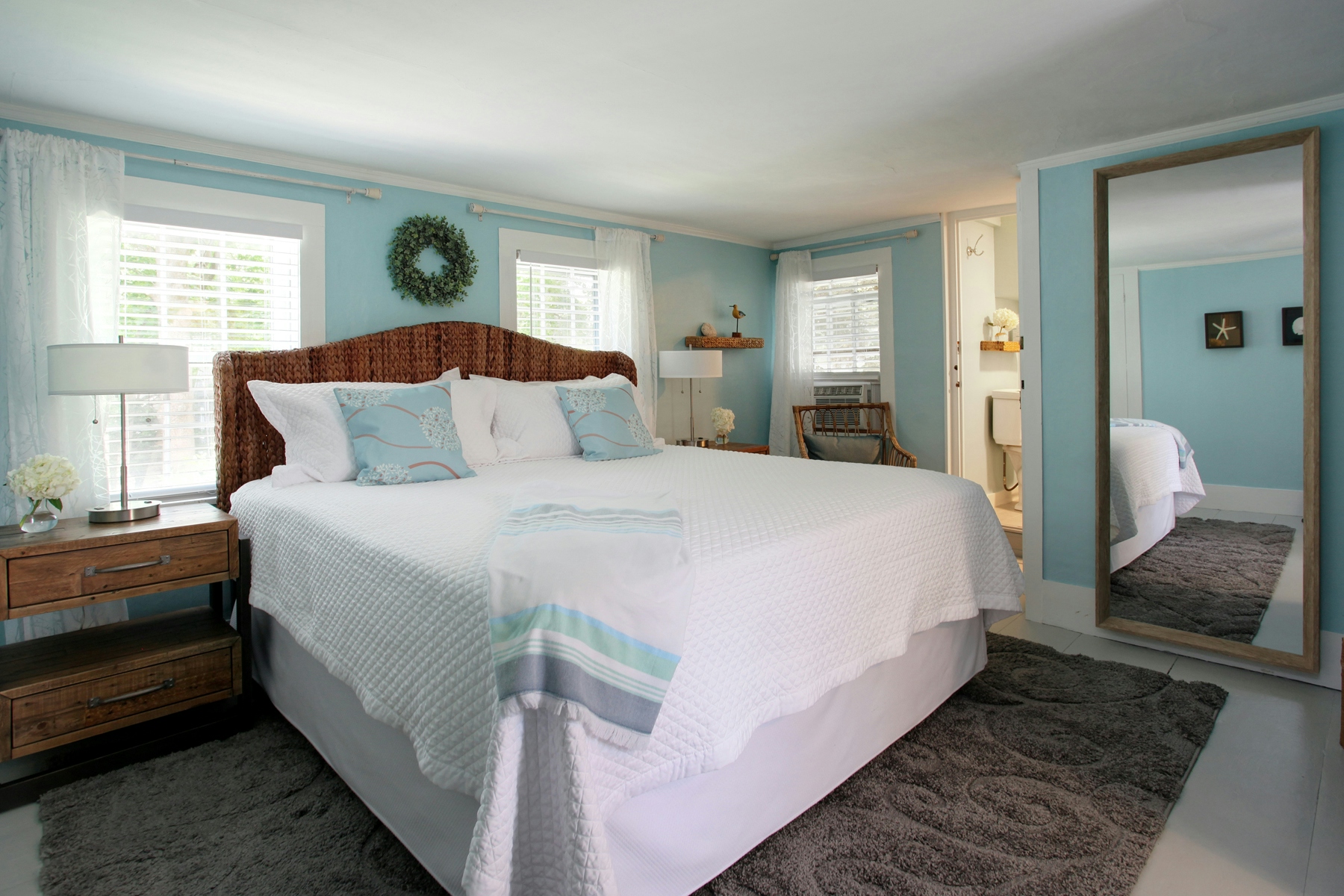 Bedroom with king bed topped with white quilted bedcover and decorative throw pillows, nightstands with lamps