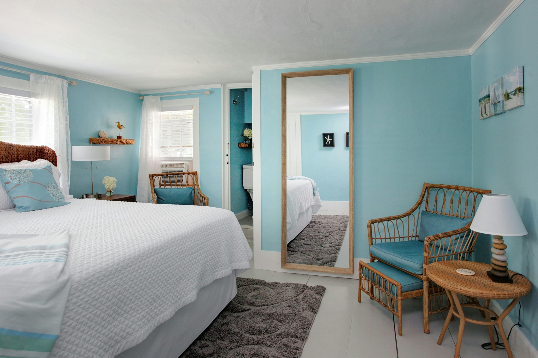 Sitting area across from bed, chair with cushions, side table with lamp