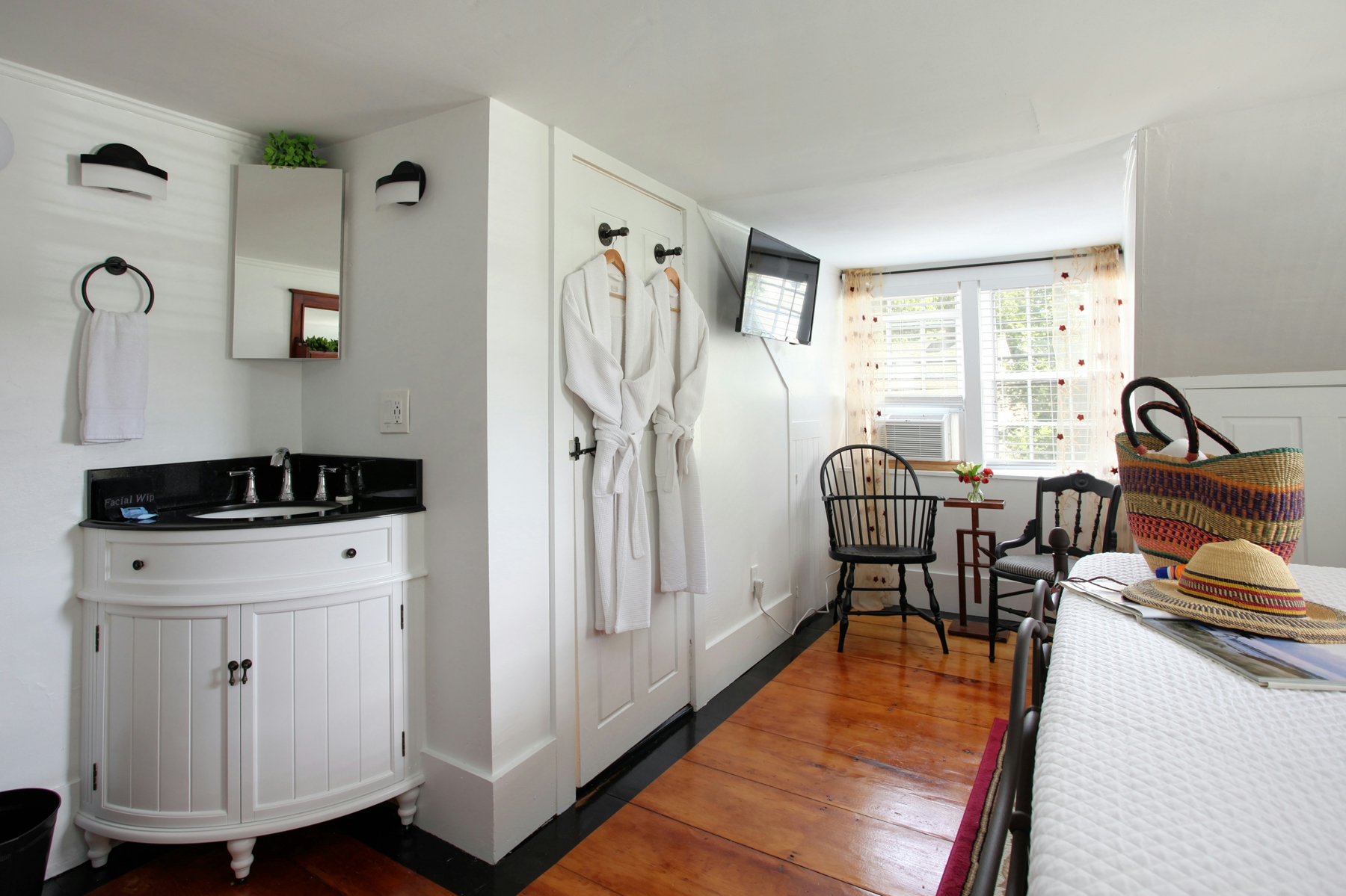 View of curved cabinet sink built in to corner of bedroom with mirror and hand towel on ring above