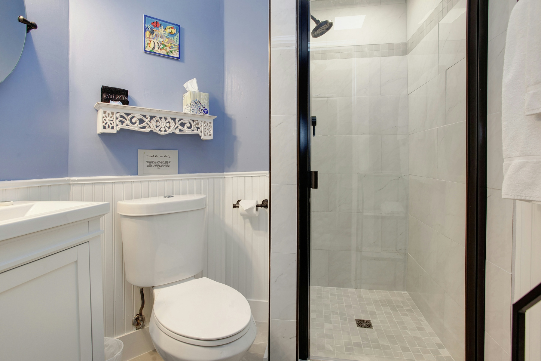 Bathroom with white vanity sink, toilet, and tiled shower