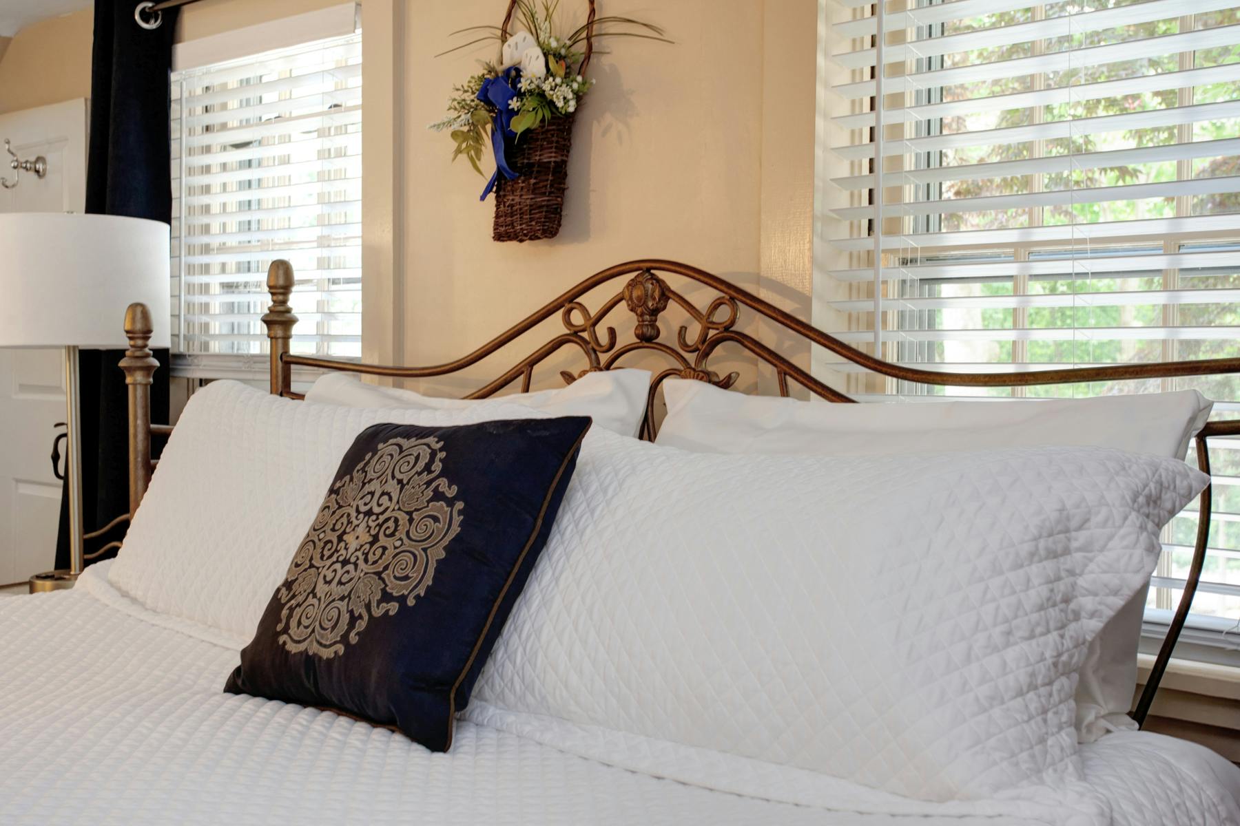 Close up of head of king size bed with white shammed pillows and decorative navy pillow
