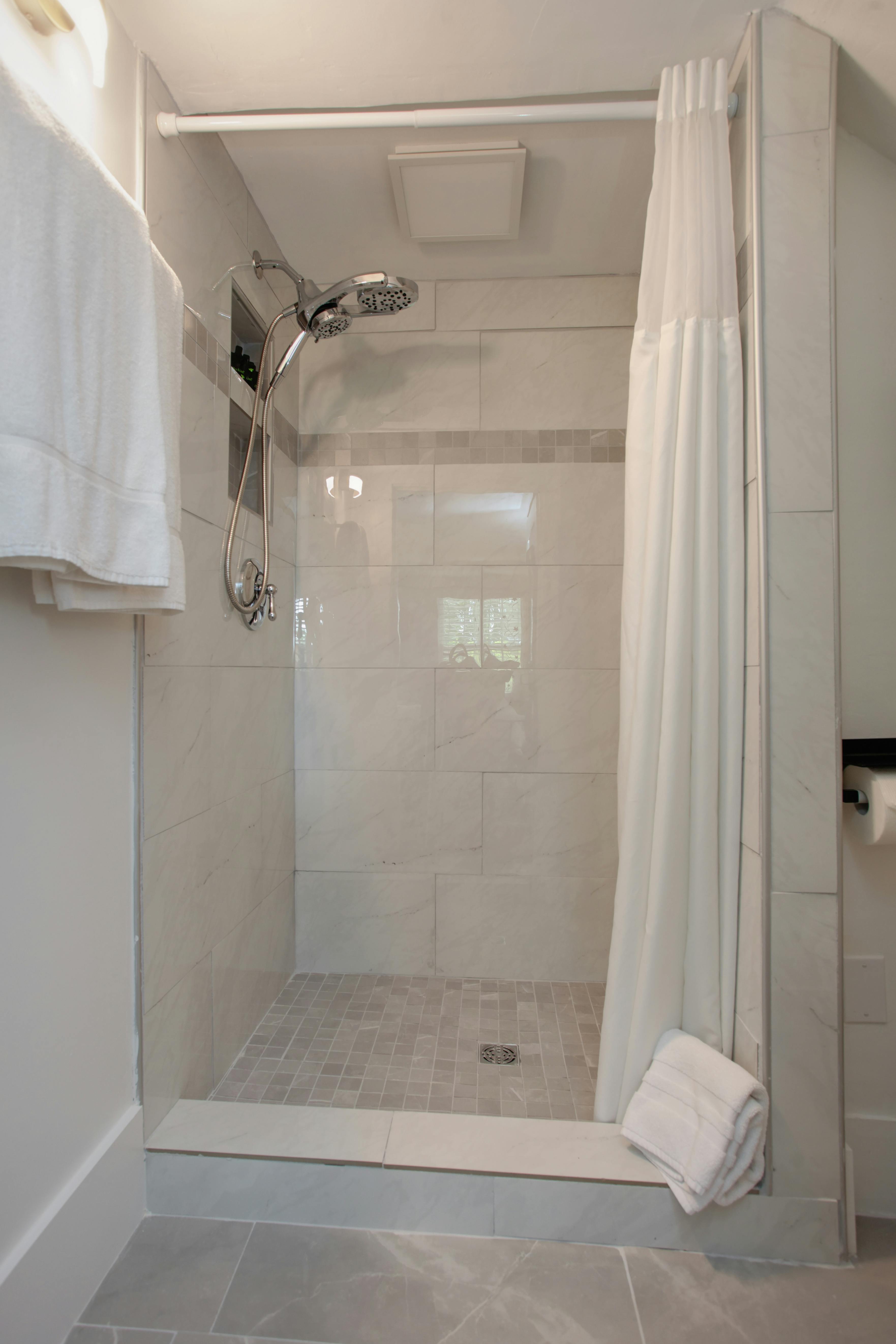 Tiled shower with silver fixtures and plush white towels on rack beside