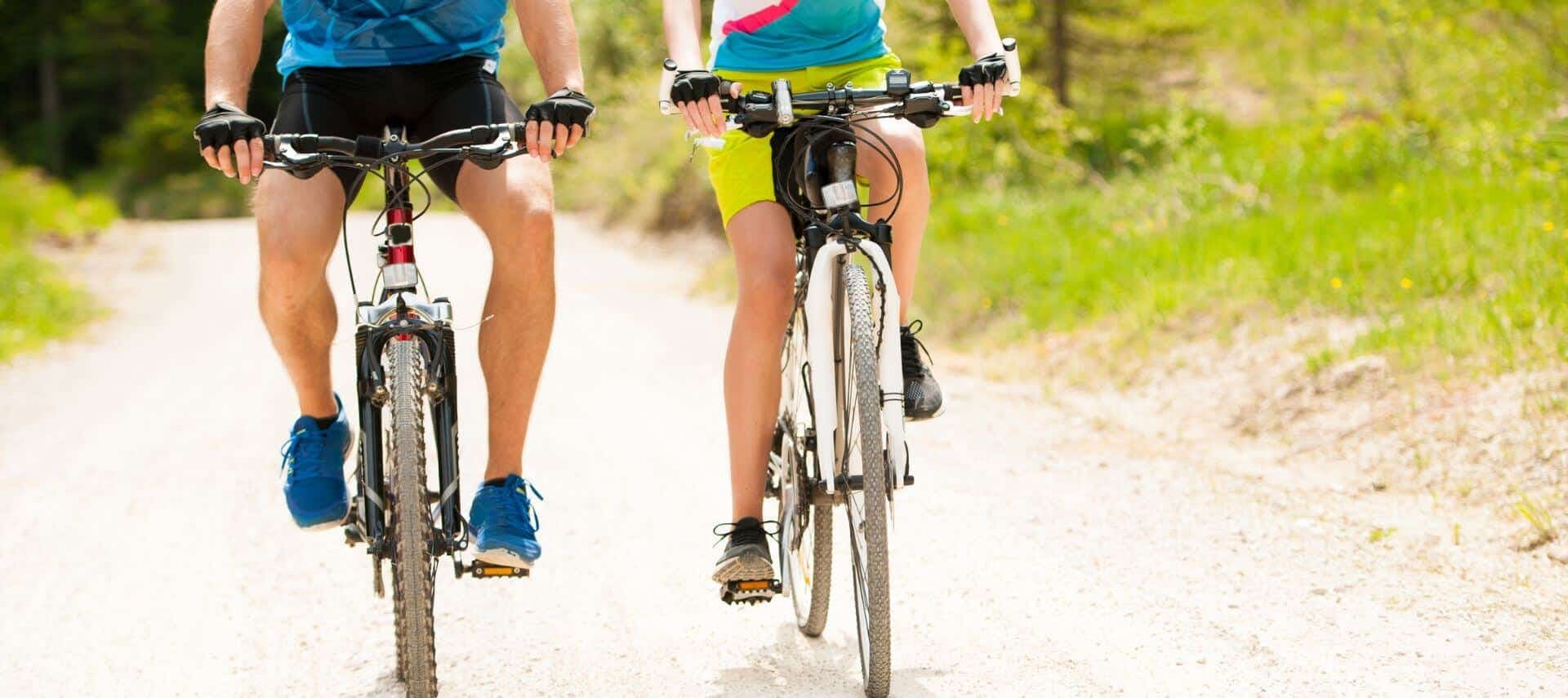 Two cyclists in shorts and tennis shoes riding the trail.