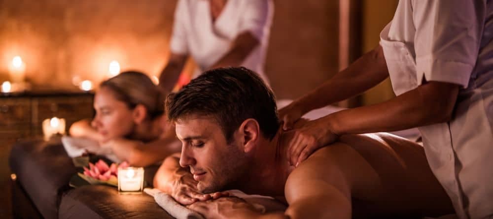 A man and woman receiving a couple’s massage in a quiet candlelit room